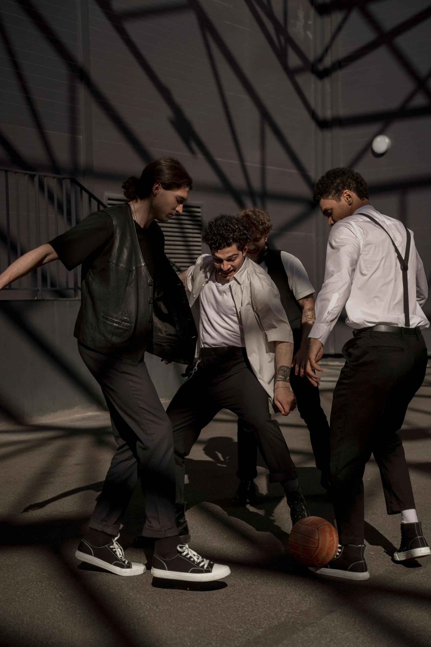 A group of four adults engage in a lively street soccer game, casting dynamic shadows.